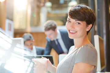 Smiling businesswoman drinking coffee in office
