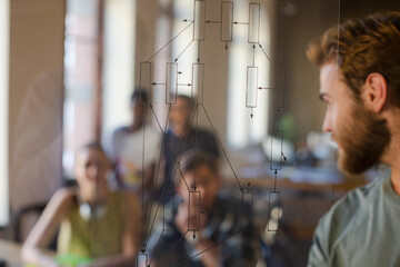 Casual businessman explaining diagram on glass in meeting