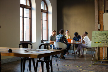 Creative business people working at tables in sunny office