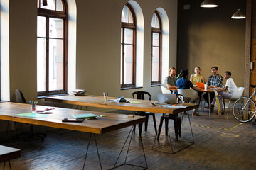 Creative business people working at tables in sunny office