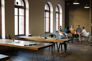 Creative business people working at tables in sunny office