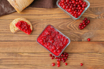 Bowl of red currant jam, berries and sandwich on wooden background