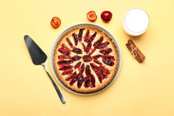 Plate with tasty plum pie glass of milk and cinnamon on color background
