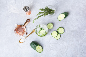 Composition with glass of cold gin tonic and cucumber slices on light background