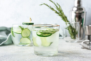 Glass of cold gin tonic and cucumber slices on light background - obrazy, fototapety, plakaty