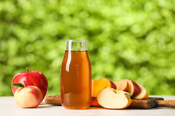 Bottle of apple juice and fresh fruits on table outdoors