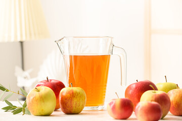 Jug of apple juice and fresh fruits on table