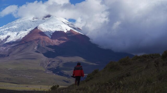 Young man walking in beautiful landscape to take photos at the top. Cotopaxi volcano, Ecuador. South America Highlands.