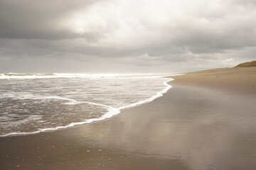 Soft waves of the sea on a sandy beach on a cloudy sky background. landscape beach