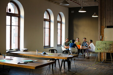 Creative business people working at tables in sunny office