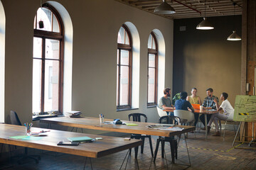 Creative business people working at tables in sunny office