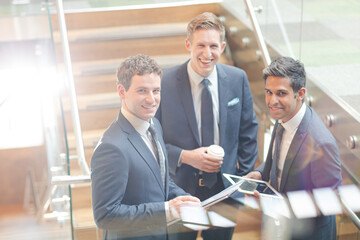 Businessmen with digital tablet and coffee talking on stairs