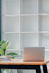 Rear view of laptop computer on wooden table in modern office room, vertical view.