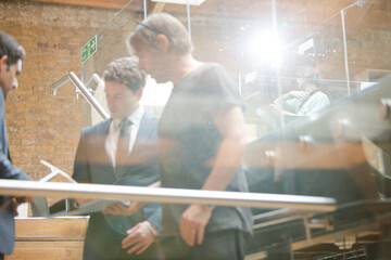 Businessmen using tablet computer outside conference room