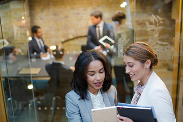 Businesswomen talking outside conference room meeting