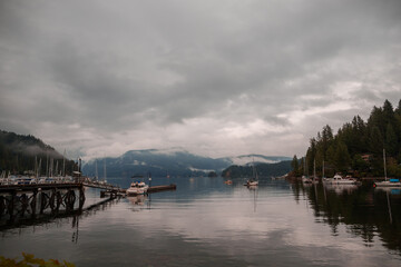 Deep cove after rain. Mountains, ocean, forest and cloudy sky. Harbor with yachts