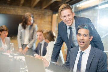 Fototapeta na wymiar Businessmen smiling at laptop in conference room meeting