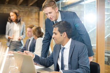 Businessmen using laptop in conference room