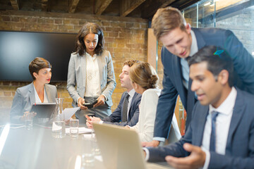 Businessmen using laptop in conference room