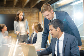 Businessmen using laptop in conference room