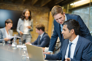 Businessmen using laptop in conference room