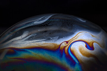 Macro picture of half soap bubble on black ground look like abstract psychedelic color planet in...