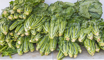 Multiple messes or bundles of fresh organic collard green in a pile or heap on a table.