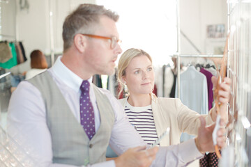 Fashion designers examining clothing on racks