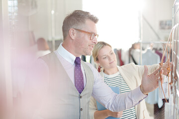 Fashion designers examining clothing on racks