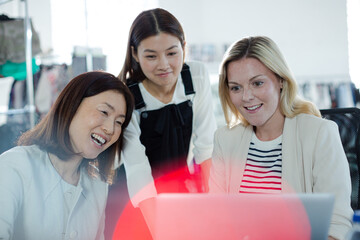 Smiling fashion designers working at laptop in office