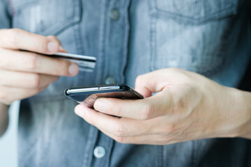 Young man sat in the living room on the sofa holding his credit card.