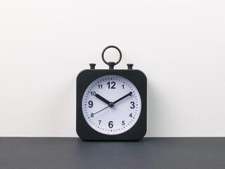 Classic alarm clock with hands on a black and gray background.