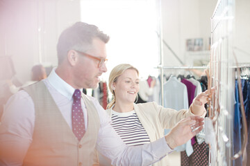 Fashion designers examining clothing on racks