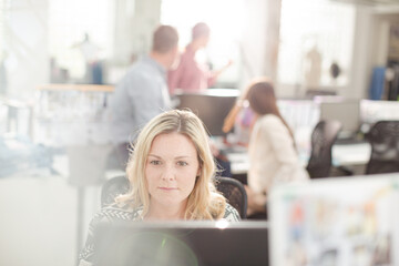 Portrait smiling fashion designer drinking coffee at computer in office