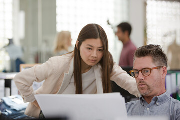 Fashion designers reviewing paperwork in office