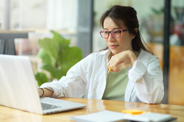 Businesswoman or college student with eyeglasses looking on laptop, working on laptop