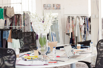 Laptop, swatches, proofs and paperwork on desk in fashion desk office