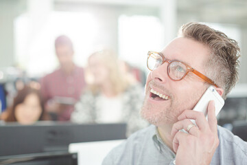 Smiling businessman talking on cell phone in office