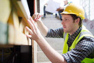 Construction worker measuring window at construction site