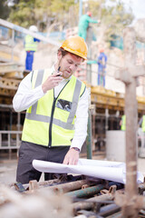 Engineer with blueprints walkie-talkie working at construction site