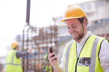 Engineer digital tablet talking on cell phone at construction site