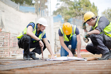 Construction workers engineer reviewing blueprints at construction site