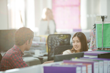 Fashion designers talking at desk in office