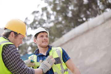 Construction worker fastening coworker‚Äö√Ñ√¥s safety harness