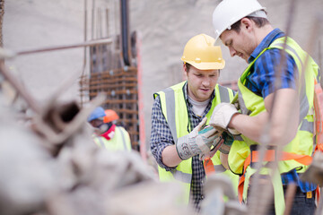 Construction worker fastening coworker‚Äö√Ñ√¥s safety harness