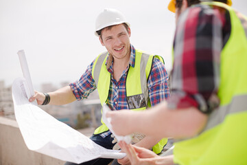 Fototapeta premium Construction worker engineer reviewing blueprints at highrise construction site