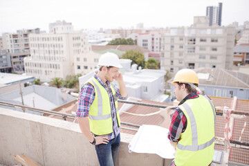Construction worker engineer reviewing blueprints at highrise construction site