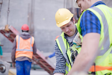 Construction worker fastening coworker‚Äö√Ñ√¥s safety harness