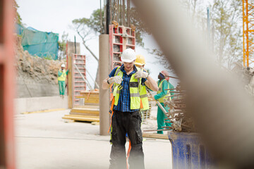 Construction worker fastening coworker‚Äö√Ñ√¥s safety harness