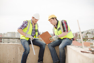 Construction worker engineer clipboard talking at highrise construction site